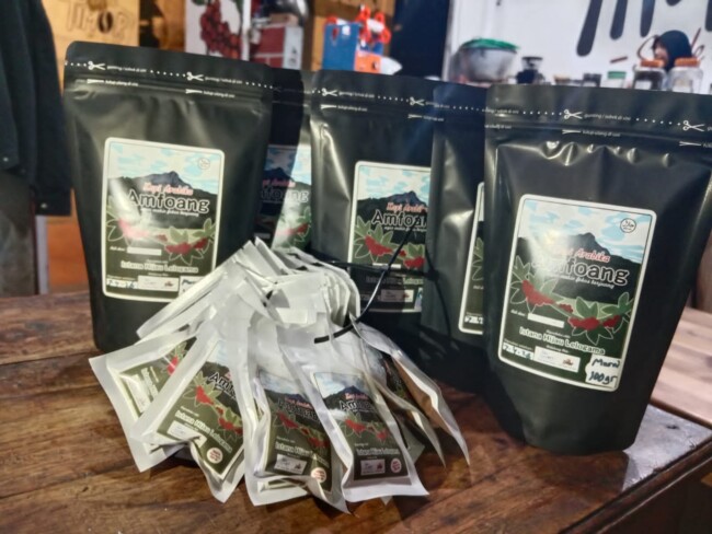 Kemasan kopi robusta Amfoang siap ekspor ke Timor Leste dengan latar kebun kopi di lereng NTT.